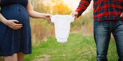 pregnant mom and dad holding onsie